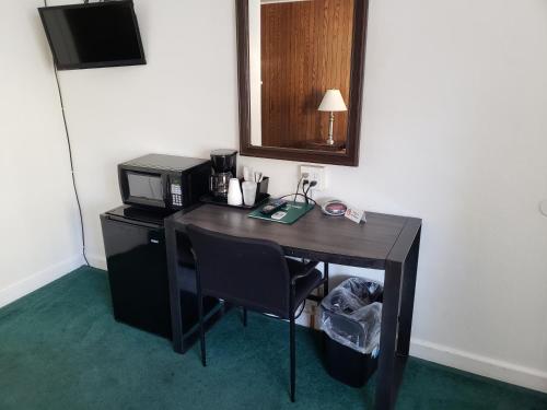 a desk in a hotel room with a microwave at Mother Lode Lodge in Mariposa