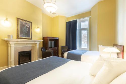 um quarto de hotel com duas camas e uma lareira em Unilofts Grande-Allée em Cidade de Quebec