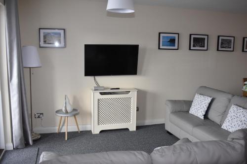 a living room with a couch and a flat screen tv at Causeway Coast Apartments Kyla Marine in Ballycastle