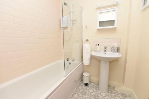 a white bathroom with a sink and a shower at Causeway Coast Apartments Kyla Marine in Ballycastle