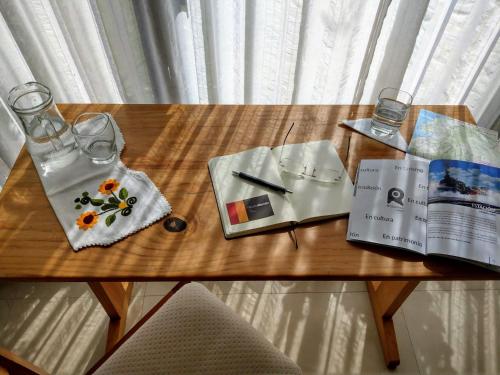 a wooden table with a book and glasses and a magazine at Hotel Rincon Aleman in Riobamba