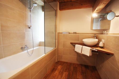 ein Bad mit einer Badewanne, einem Waschbecken und einer Dusche in der Unterkunft hotel rainhof scheune & naturpark restaurant (Kirchzarten) in Kirchzarten