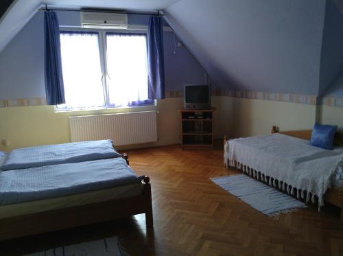 een slaapkamer op zolder met 2 bedden en een televisie bij Főnix Fogadó in Lenti