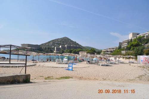 a sandy beach with umbrellas and the ocean at Župa Dubrovačka Guest House in Mlini