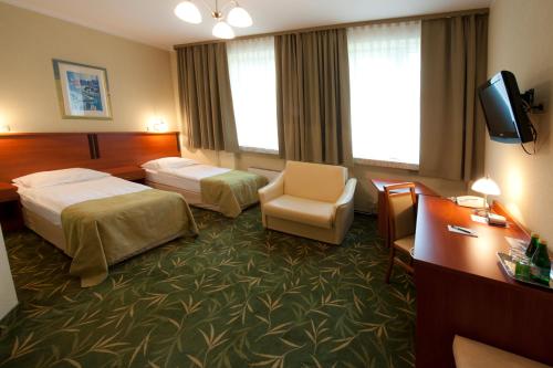 a hotel room with two beds and a chair at Brojan in Jaworzno