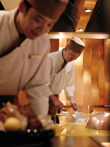 two chefs standing in a kitchen preparing food at Kowloon Shangri-La, Hong Kong in Hong Kong