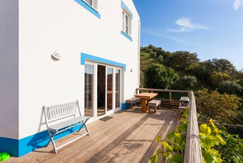 a house with a deck with a bench and a table at Romantic riverside retreat in Odemira