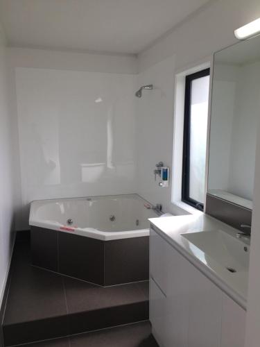 a white bathroom with a tub and a sink at Grosvenor Motel in Hamilton