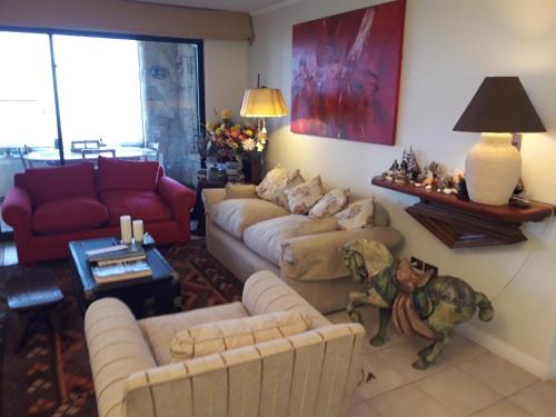 a living room with couches and a red couch at B&B Santo Domingo Chile ENGLISH SPOKEN Gran Departamento compartido frente al mar PARQUE TRICAO bird sanctuary 14kms 9miles away DESAYUNO ESTACIONAMIENTO Y WIFI GRATIS Free parking wifi and breakfast in Santo Domingo
