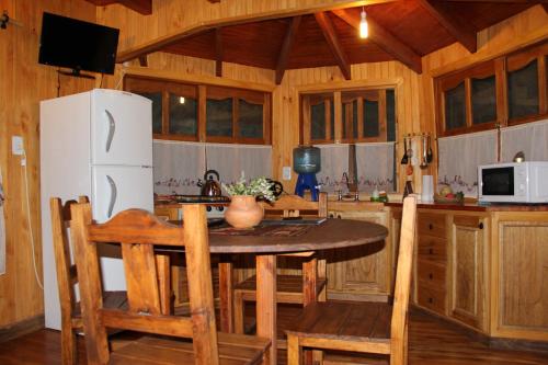 a kitchen with a table and a white refrigerator at Cabanas Inti-Wari Jujuy in El Ceibal
