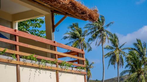 a building with palm trees in the background at Mango Lodge in Selong Belanak