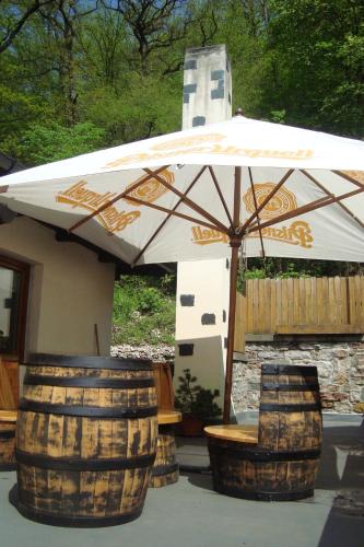 a white umbrella and two barrels and a bench at Restaurant a penzion Pod Draci skalou in Karlštejn