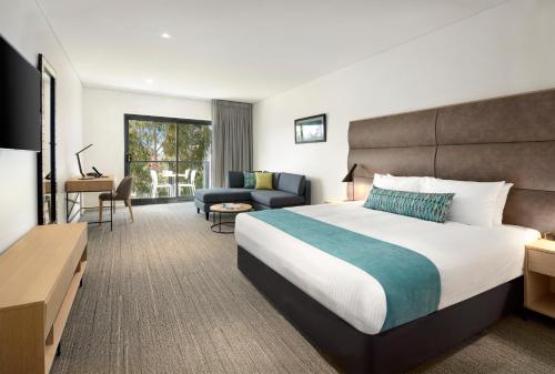 a hotel room with a large bed and a couch at Quality Hotel Lakeside in Bendigo