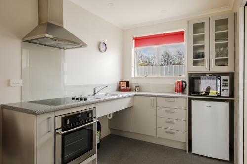 a white kitchen with a sink and a stove at Esplanade Motels in Gore