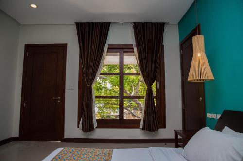 a bedroom with a bed and a window with curtains at Karancho Beach House in Mactan