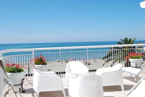 a balcony with white chairs and a view of the beach at Hotel Villa Eleonora in Scauri