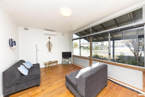 a living room with two couches and a large window at Douglas Cottage in Forster