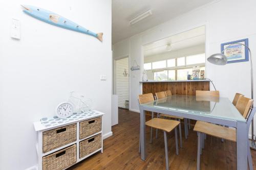 a dining room with a blue table and chairs at Douglas Cottage in Forster