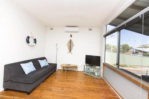 a living room with a couch and a tv at Douglas Cottage in Forster