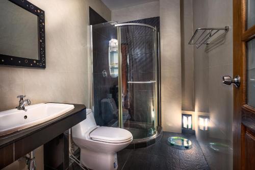 a bathroom with a shower and a toilet and a sink at Baan Georges Hotel in Sukhothai