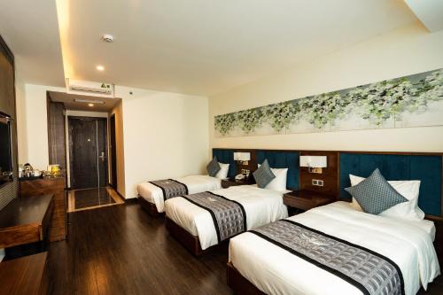 a hotel room with three beds and a painting on the wall at Eagle Hotel in Ha Tinh