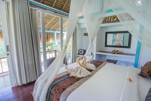 a bedroom with a bed with a mosquito net at Water Blow Huts in Nusa Lembongan
