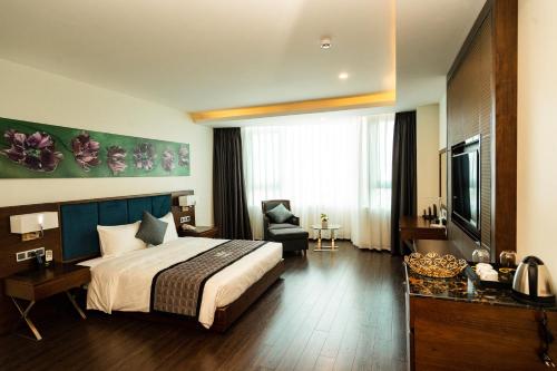 a bedroom with a bed and a chair and a television at Eagle Hotel in Ha Tinh