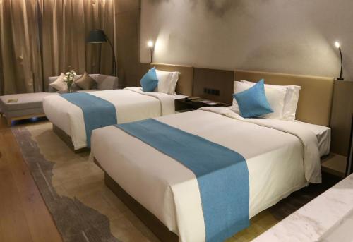 a hotel room with two beds with blue and white sheets at Novotel Deqing Moganshan in Deqing