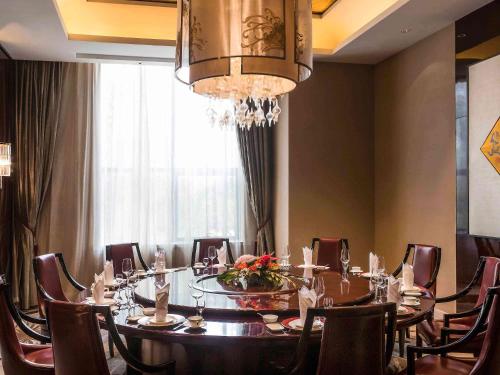 a dining room with a table and chairs and a chandelier at Pullman Weifang in Weifang