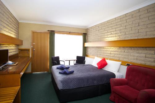 a hotel room with a bed and a red chair at Glynlea Motel in Horsham