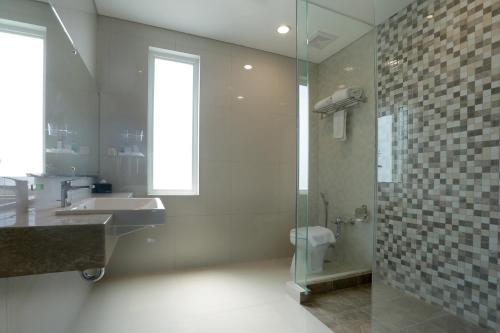 uma casa de banho com um chuveiro, um lavatório e um WC. em PrimeBiz Hotel Surabaya em Surabaia