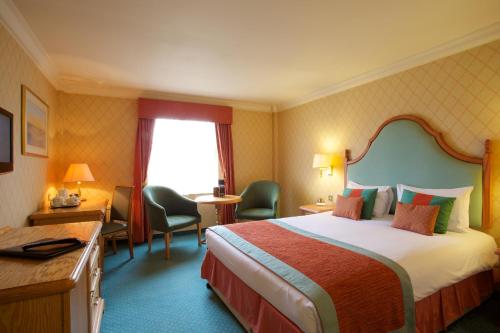 a hotel room with a bed and chairs and a window at Coulsdon Manor Hotel and Golf Club in Croydon