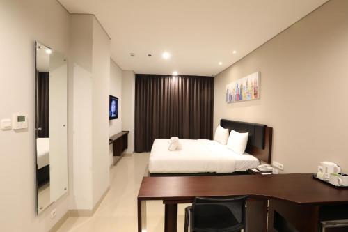 a hotel room with a bed and a desk at PrimeBiz Hotel Surabaya in Surabaya