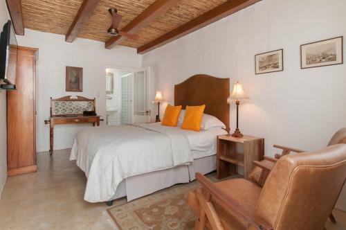 a bedroom with a bed and a chair at Hotel Roosje van de Kaap in Swellendam