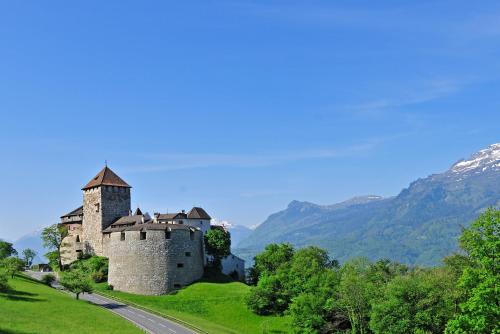 a castle on a hill with mountains in the background at Hotel Vaduzerhof by b-smart in Vaduz