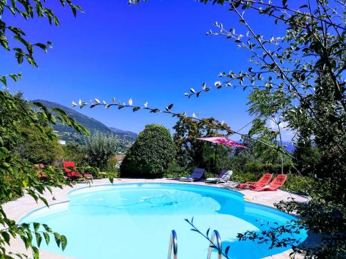 ein Pool in einem Resort mit Stühlen und einem Sonnenschirm in der Unterkunft Villa Côte d'Azur piscine privée in La Gaude