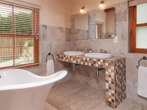 a bathroom with two sinks and two mirrors at Hotel Roosje van de Kaap in Swellendam