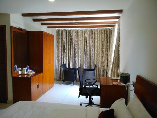 a hotel room with a bed and a desk and chairs at Mrugavani Resort & Spa in Hyderabad