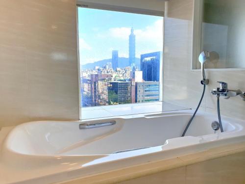 a bathroom with a bathtub and a large mirror at Eastin Taipei Hotel in Taipei