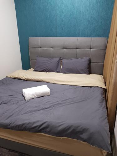 a bed with a headboard and a white towel on it at SHAHALAM ALLBESS@TREFOIL in Setia Alam