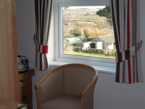 a chair sitting in a room with a window at Beacon Country House Hotel & Luxury Shepherd Huts in St. Agnes 