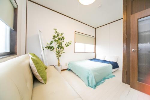 a bedroom with a bed and a couch and a window at 7 min to JR Yokkaichi STN Large House in Yokkaichi