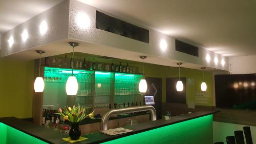 a bar in a restaurant with green lighting at Bergschänke & Berghotel in Bresinchen
