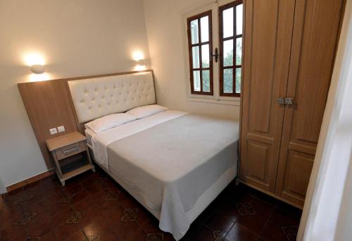 a small bedroom with a bed and a window at Olivegrove House in Vourvourou