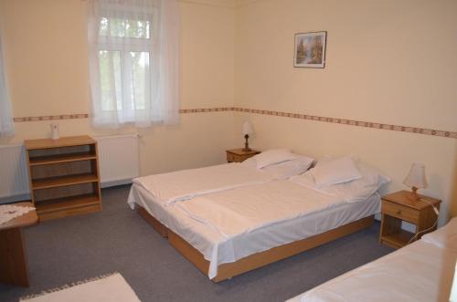 a bedroom with a bed and two tables and a window at Békástó Panzió Diósjenő in Diósjenő