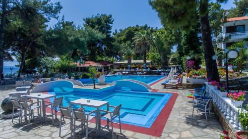a pool at a resort with tables and chairs at Porfi Beach Hotel in Nikiti