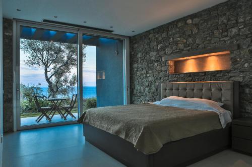 a bedroom with a bed and a large glass window at Infinity Villa in Plomarion