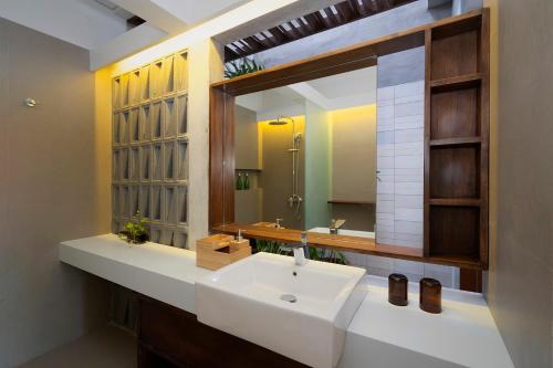 a bathroom with a white sink and a mirror at The Kemilau Hotel & Villa Canggu Bali in Canggu