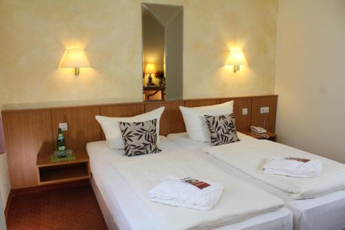 two beds in a hotel room with towels on them at Hotel Weisser Schwan in Erfurt