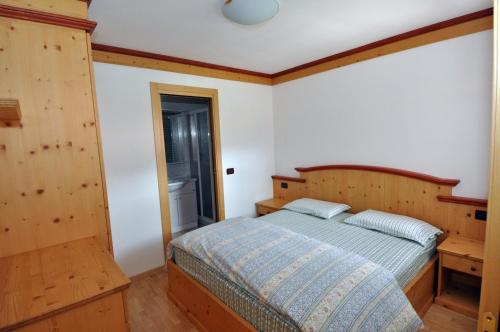 - une chambre avec un lit et une tête de lit en bois dans l'établissement Villetta Giumella, à Pozza di Fassa